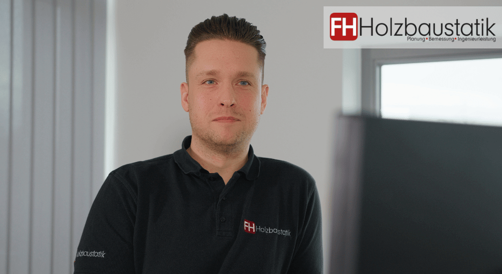 Die erfahrenen Statiker von FH Holzbaustatik sind Ihre vertrauensvollen Statiker in Düsseldorf. Auf dem Bild ist ein sehr erfahrener Spezialist unserer Firma zu sehen, der ein schwarzes Poloshirt mit dem Logo unseres Ingenieurbüros trägt.